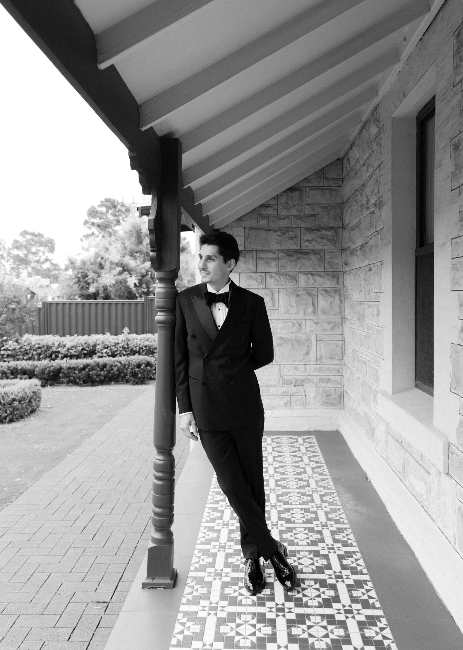 Three black and white photos show someone in formal attire posing along a covered stone walkway with pillars.