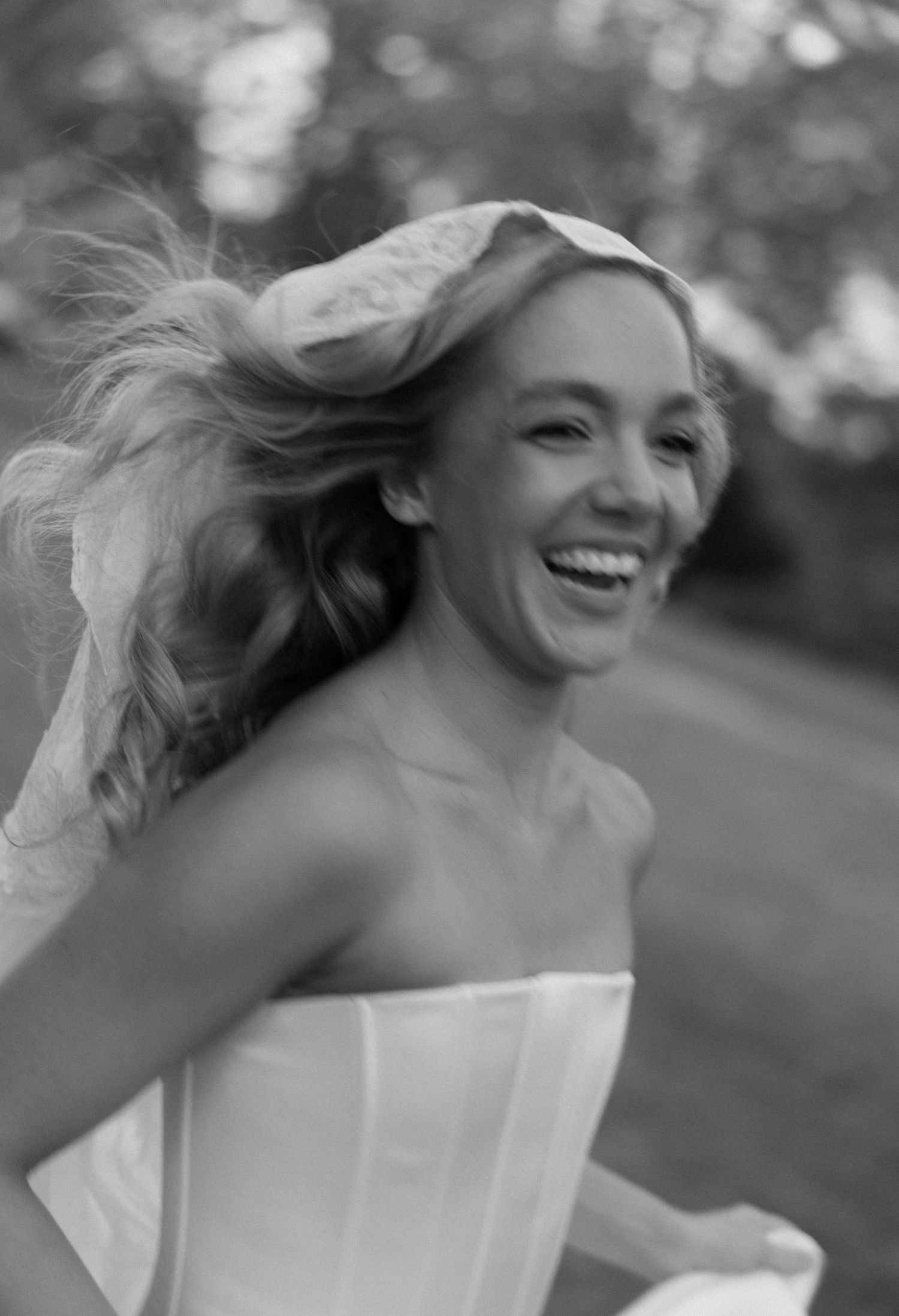 A sequence of joyful moments captured in black and white as a bride in a strapless gown twirls outdoors.