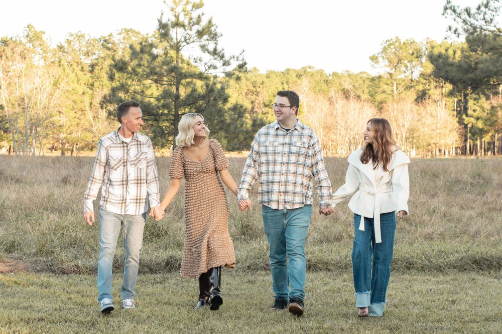 Group walking together through field at sunset wearing casual autumn attire.