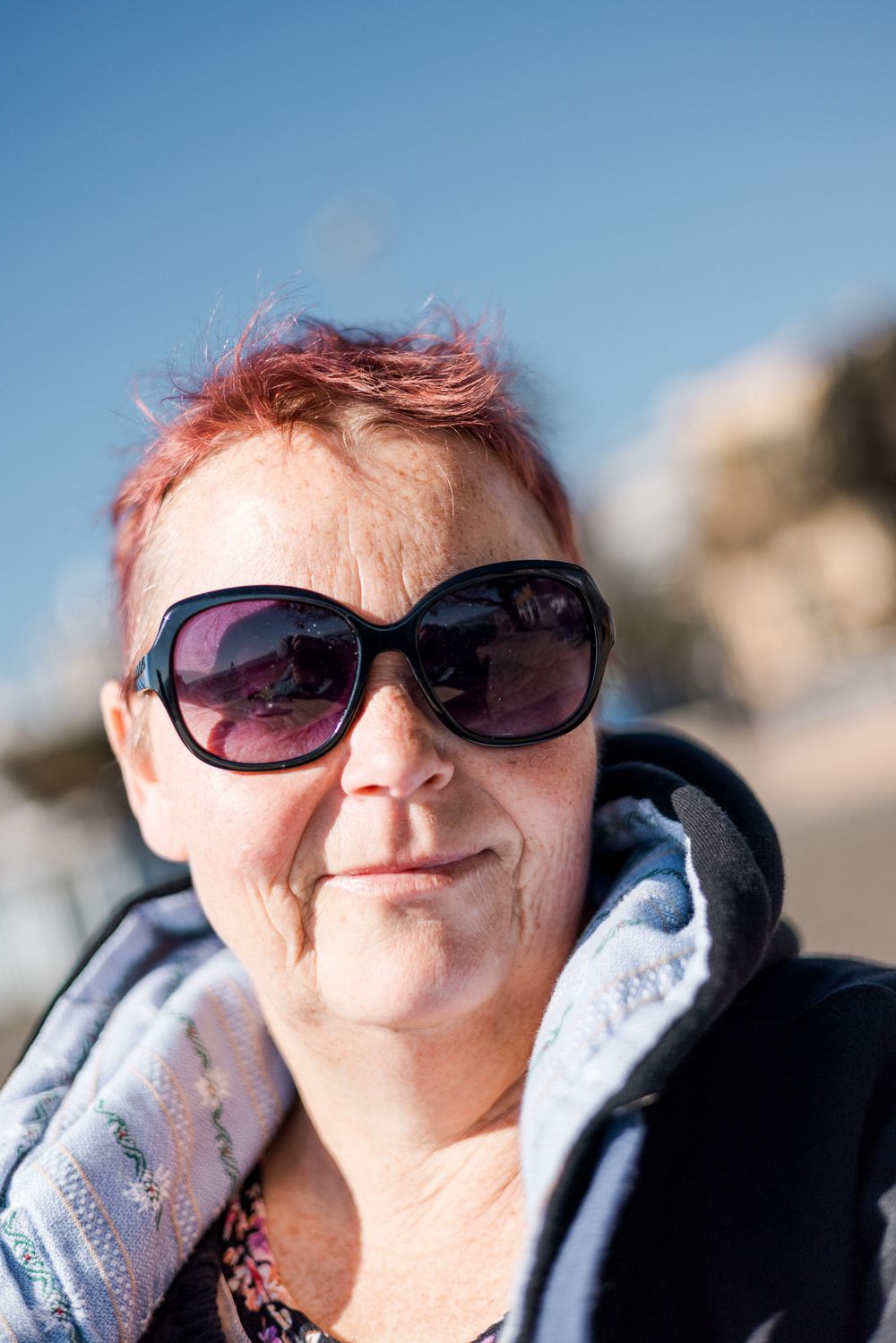 Eight close-up portraits showing a person with red hair and sunglasses against a blue sky background.