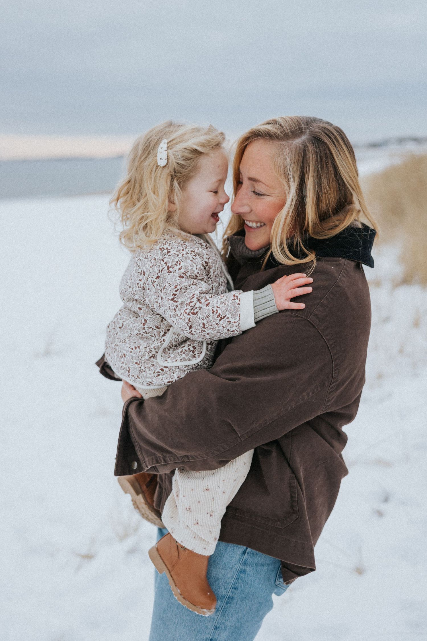 Two people in cozy white knit sweaters share an intimate embrace outdoors.