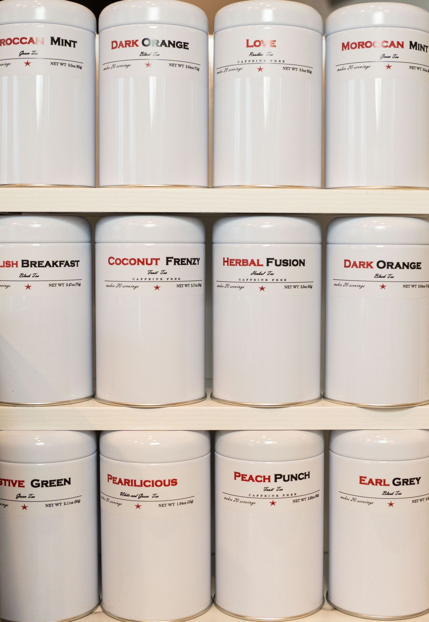 Organized shelf of white tea canisters with various flavor labels.