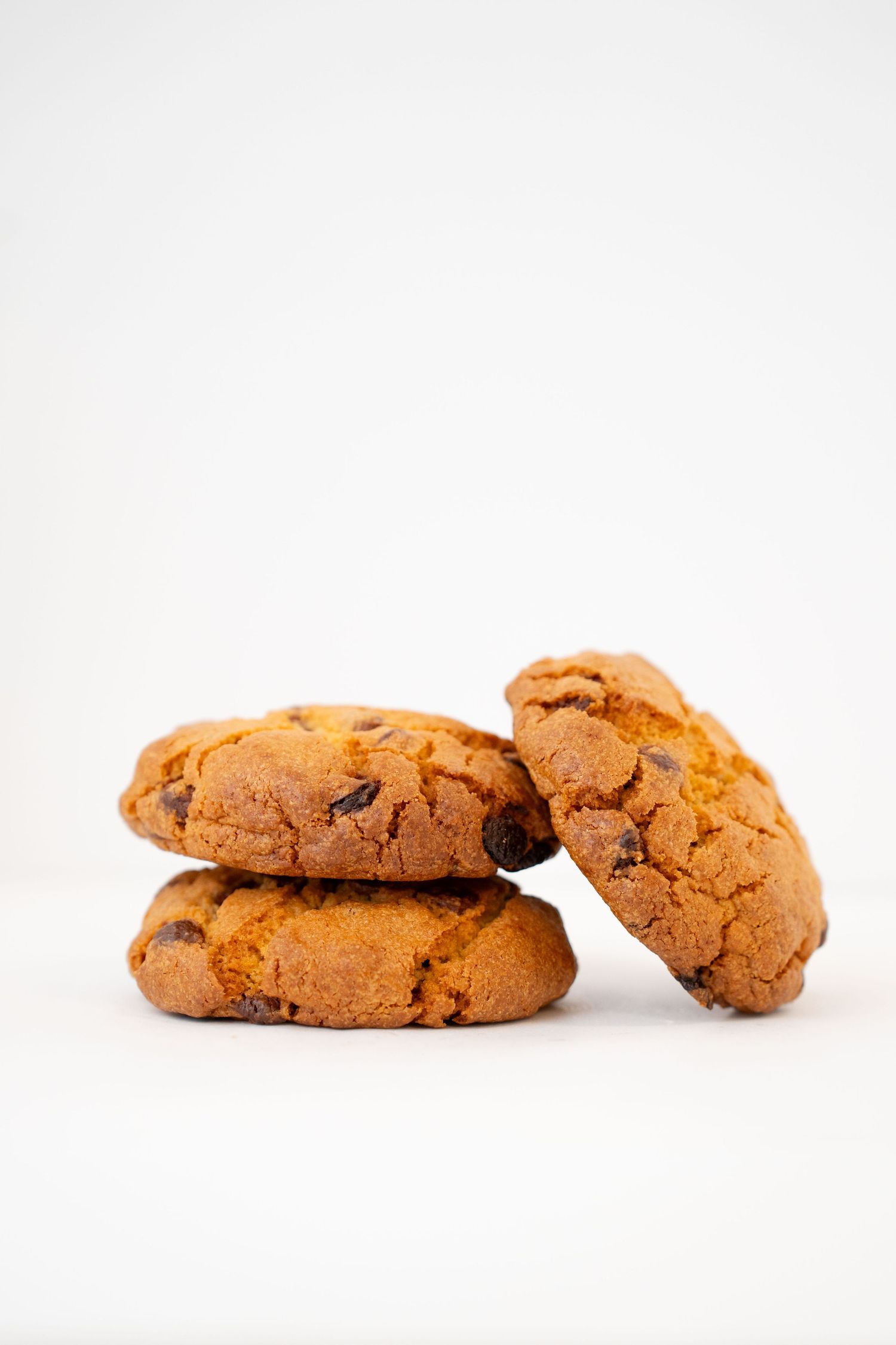 Stack of golden brown chocolate chip cookies against white background.