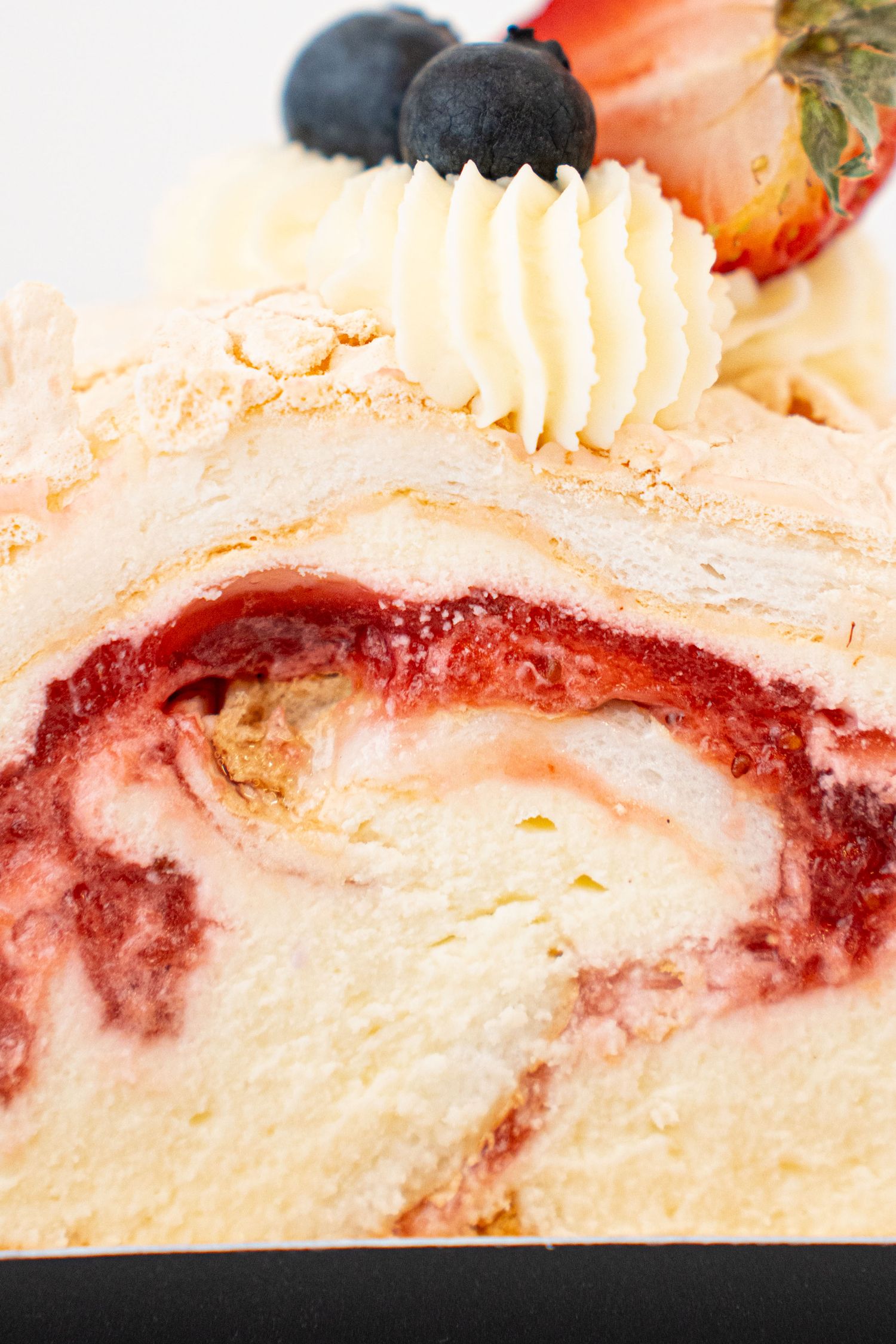 Strawberry swirl cheesecake slice garnished with berries and whipped cream.
