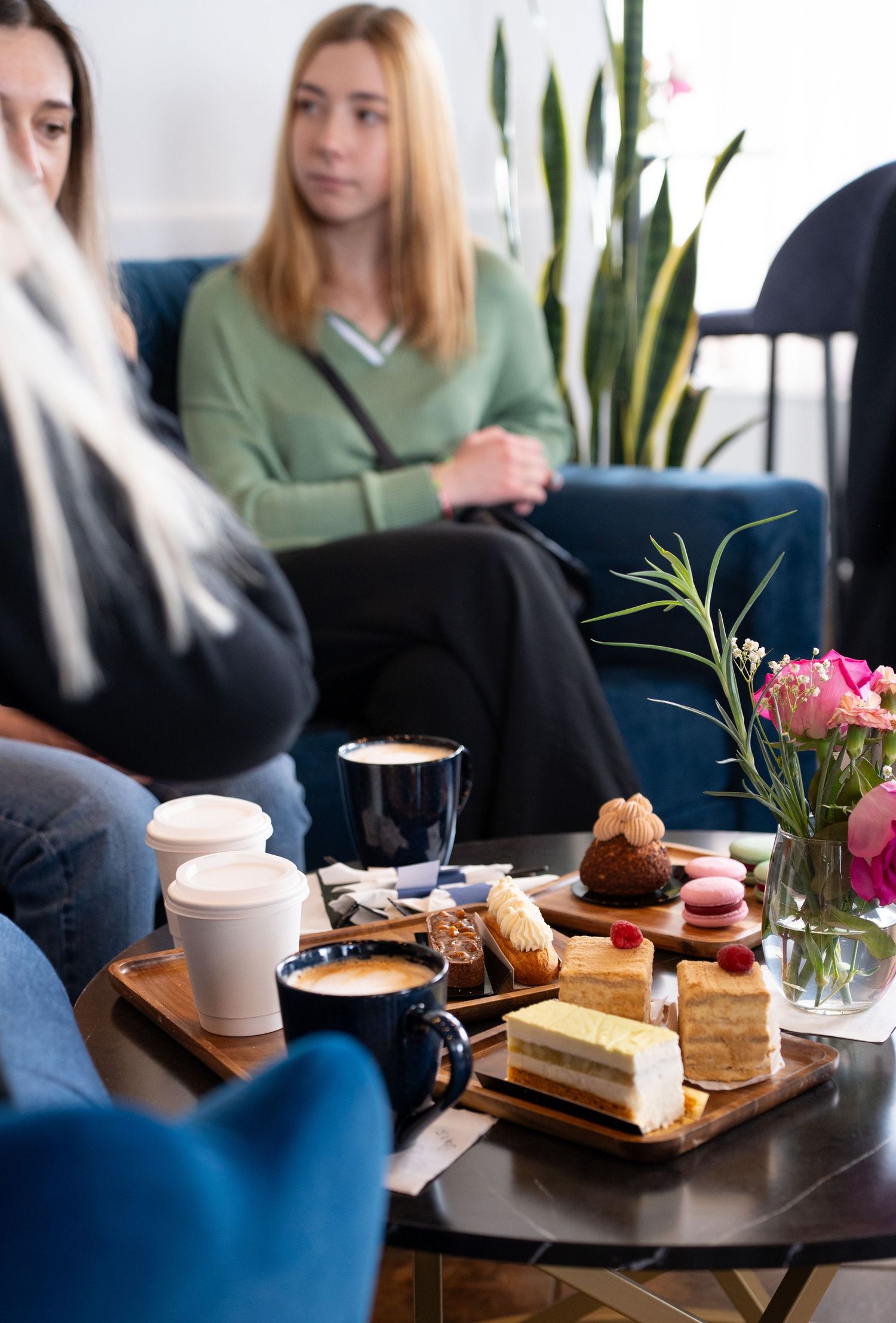Coffee and pastries served on a wooden board with flowers in a cafe setting.