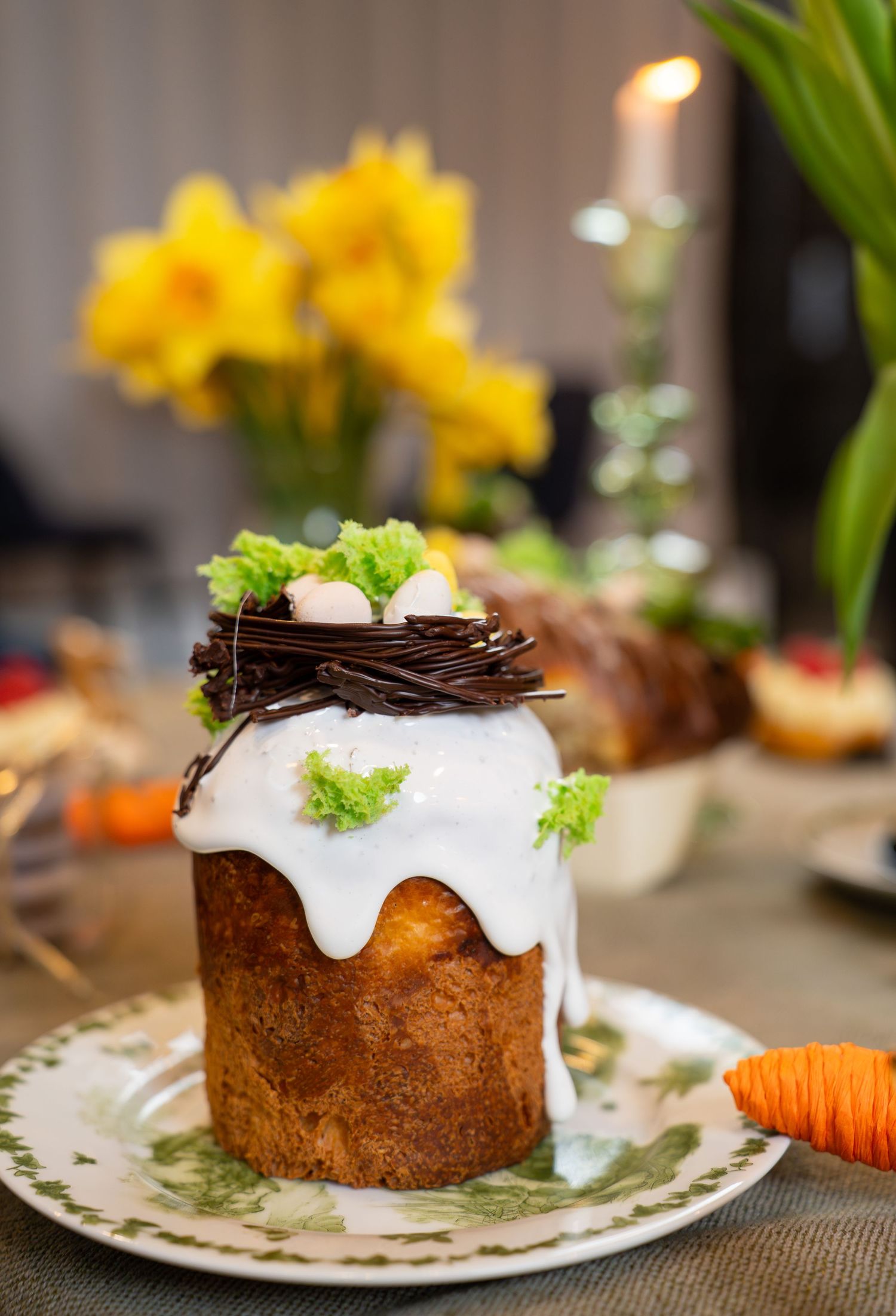 Tall pastry with white glaze and chocolate nest decoration garnished with fresh herbs.