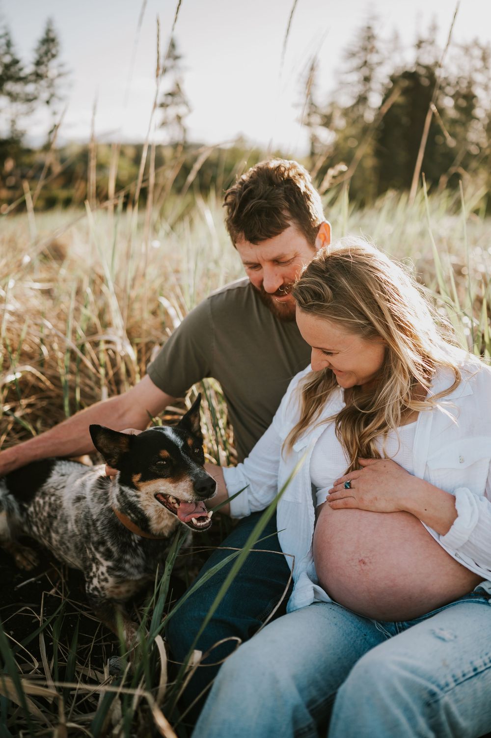 Beautiful maternity portrait of couple sitting in Comox Valley beach grass with dog. Photography by Photographer Soulfull Photographs