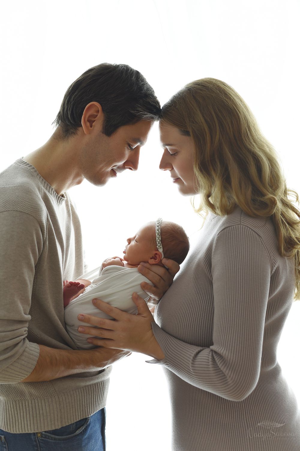 A sequence of intimate maternity photos showing a couple in white embracing and looking at their baby bump.