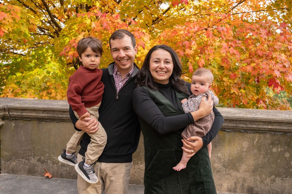 A group enjoying a fall photoshoot outdoors with vibrant orange and yellow autumn foliage in the background.