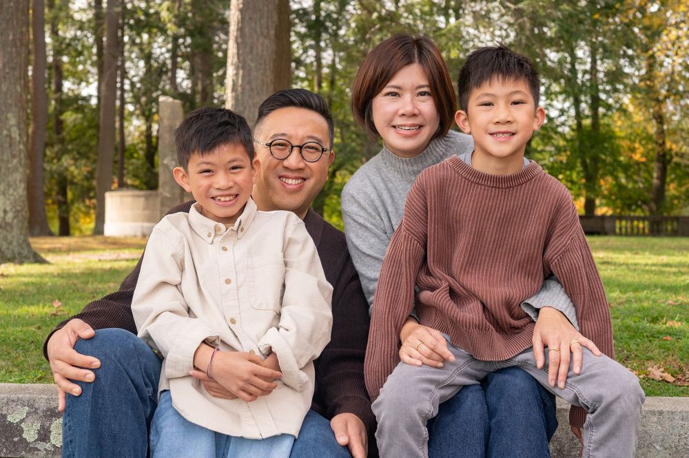 A group sits together outdoors in casual clothing against a natural autumn background during a photo session.