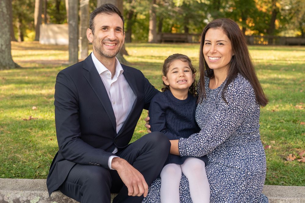 A happy family enjoying a warm autumn day together in a sunlit park setting.