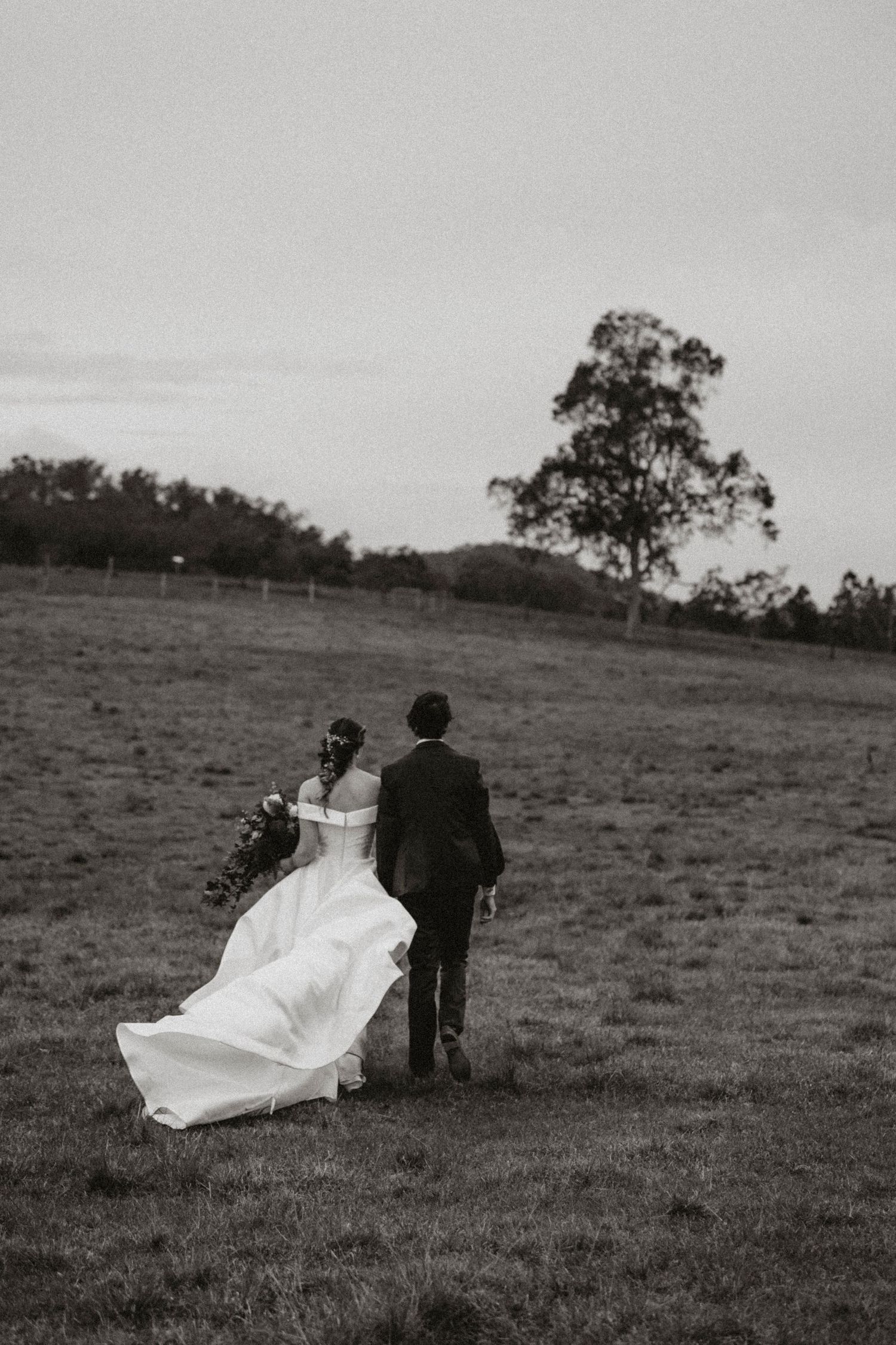 Couple sharing intimate moment against rustic fence line at sunset in countryside setting.