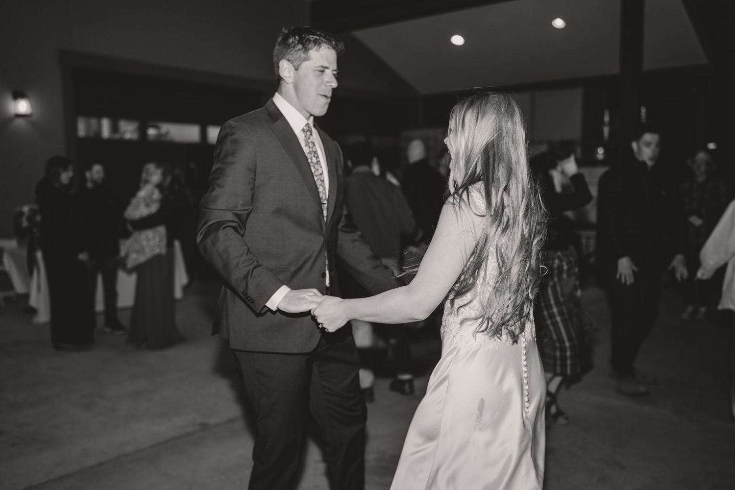 Couple dancing together at an elegant indoor reception venue in black and white.
