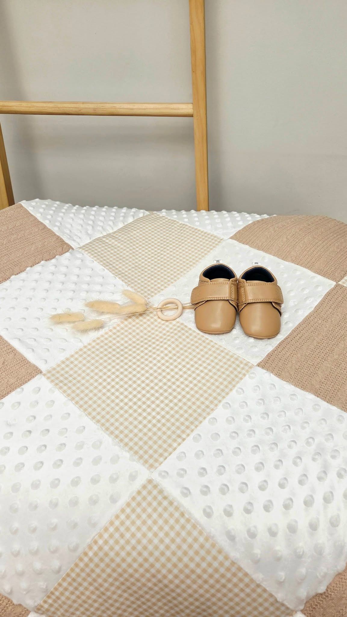 Cozy bedroom interior with neutral bedding, gingham pillows and woven textures in warm tones.
