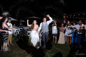 Guests celebrate during a festive outdoor wedding reception under string lights at night.