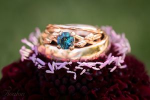 Rose gold wedding rings with blue stone nestled on purple flower petals.