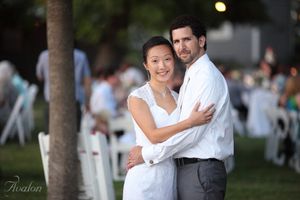 A couple embraces during their outdoor evening wedding reception.