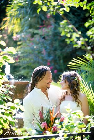 Couple sharing an intimate moment in a lush tropical garden setting.