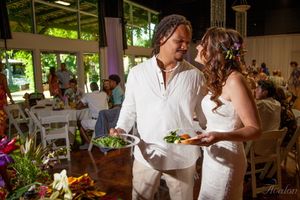 Newlyweds share an intimate moment while serving food at their casual outdoor wedding reception.