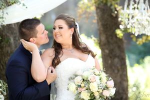 Romantic wedding portrait featuring loving moment between newlyweds with bridal bouquet.