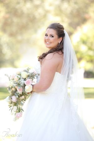 Bridal portrait in natural lighting showcasing wedding gown and floral bouquet.