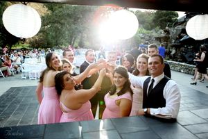 Wedding party having fun during a reception with pink dresses and white paper lanterns overhead.