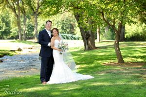 A wedding couple poses together on a lush green lawn during their summer ceremony.