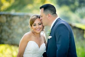 A romantic wedding moment captured outdoors with soft natural lighting and greenery in the background.