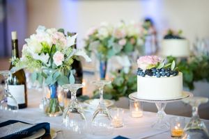Elegant wedding reception table with floral centerpieces, candles and a white wedding cake.
