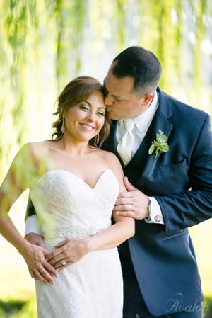 Romantic wedding portrait under willow trees with soft natural lighting.