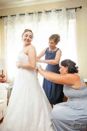 Wedding preparation scene showing final dress adjustments in a sunlit room.