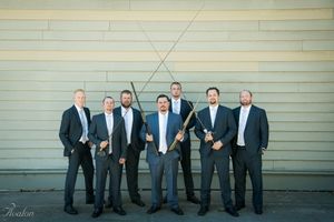 Groomsmen in navy suits posing together against a light colored wall.