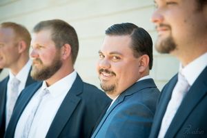 Wedding party members in navy suits sharing a candid moment outdoors.