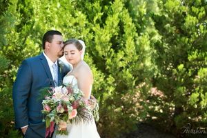 Wedding couple sharing an intimate moment against lush green foliage.