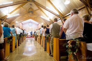 Interior view of wedding ceremony in wooden chapel with guests seated in pews.