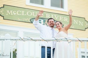 Newlyweds wave from balcony of yellow McCloudver Inn building.