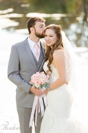 Romantic wedding portrait of couple with pink bouquet and soft lighting.