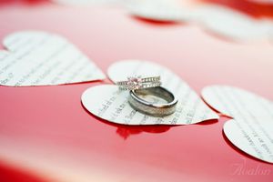 Wedding rings photographed on decorative paper hearts with romantic lighting.