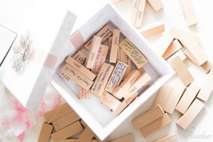 Wooden Jenga blocks arranged in white box with pink flower petals.
