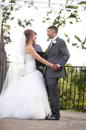 A couple shares a romantic moment during their wedding ceremony under a pergola.