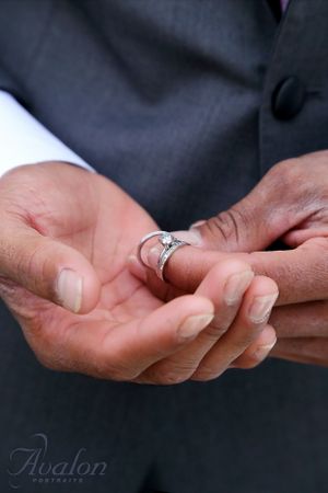 Close-up of hands holding a silver wedding ring.