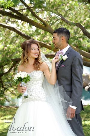 Wedding couple poses together in garden setting with spring blossoms.
