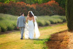 Couple walks hand in hand down rural path at sunset.