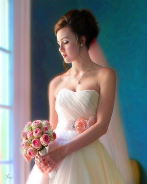 Bride in strapless wedding dress holds pink rose bouquet against turquoise background.