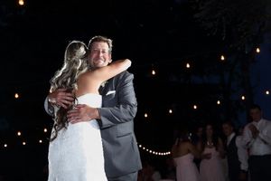 Intimate dance moment captured at nighttime wedding reception with twinkling lights.