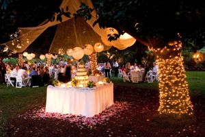 An outdoor wedding reception setup with string lights and illuminated trees creating a magical ambiance.