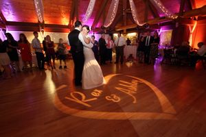 Romantic first dance with heart-shaped spotlight projection on wooden dance floor.