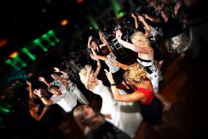 Wedding reception dance party with guests celebrating on crowded dance floor.