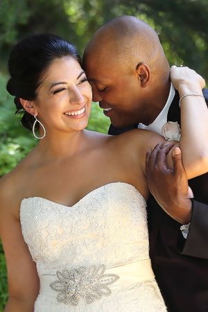 A tender wedding portrait moment captured outdoors with natural greenery in the background.