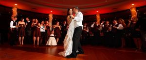 A romantic first dance between newlyweds in a ballroom with red ambient lighting.